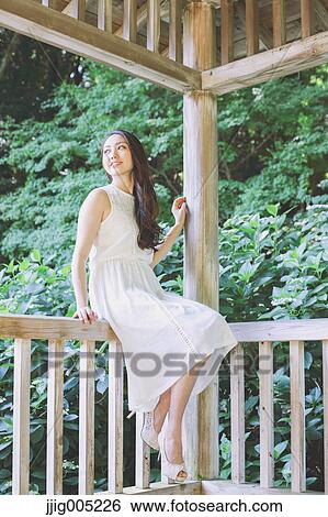 Young Japanese woman on wooden deck in a city park View Large Photo Image Stock Photograph - Young Japanese woman on wooden deck in a city park. Fotosearch