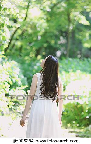 Young Japanese woman surrounded by green in a city park View Large Photo Image Picture - Young Japanese woman surrounded by green in a city park. Fotosearch