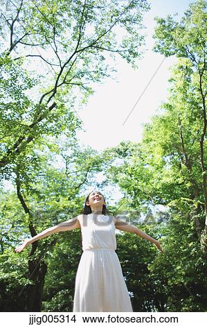 Young Japanese woman surrounded by green in a city park View Large Photo Image Picture - Young Japanese woman surrounded by green in a city park. Fotosearch