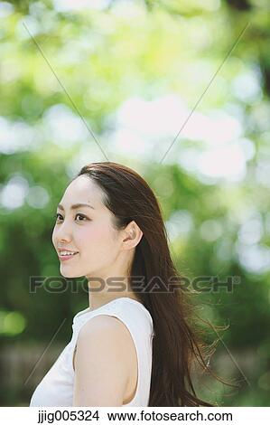 Young Japanese woman surrounded by green in a city park View Large Photo Image Picture - Young Japanese woman surrounded by green in a city park. Fotosearch