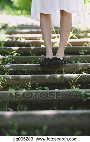 Stock Image - Young Japanese woman surrounded by green in a city park. Fotosearch