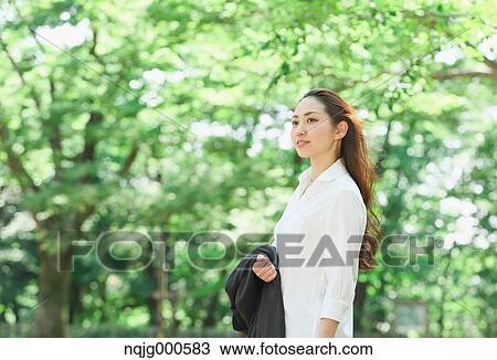 Young Japanese woman surrounded by green in a city park View Large Photo Image Stock Image - Young Japanese woman surrounded by green in a city park. Fotosearch