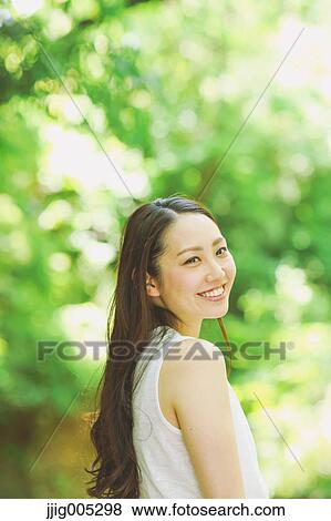 Stock Photo - Young Japanese woman surrounded by green in a city park. Fotosearch