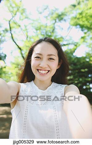 Stock Photo - Young Japanese woman surrounded by green in a city park. Fotosearch