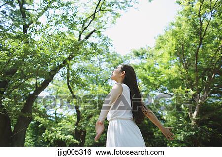 Young Japanese woman surrounded by green in a city park View Large Photo Image Stock Photograph - Young Japanese woman surrounded by green in a city park. Fotosearch
