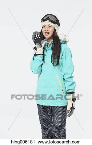 Stock Image - Young Japanese woman wearing snowboard wear on white background. Fotosearch