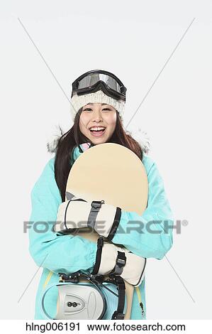 Stock Image - Young Japanese woman wearing snowboard wear on white background. Fotosearch