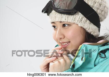 Stock Image - Young Japanese woman wearing snowboard wear on white background. Fotosearch