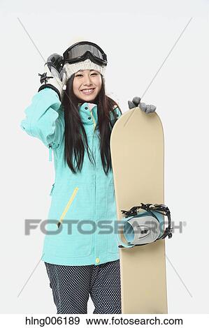 Stock Photo - Young Japanese woman wearing snowboard wear on white background. Fotosearch