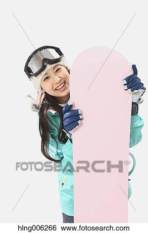 Stock Photograph - Young Japanese woman wearing snowboard wear on white background. Fotosearch
