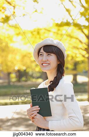 Young Japanese woman with book in a city park View Large Photo Image Stock Image - Young Japanese woman with book in a city park. Fotosearch