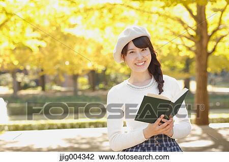 Young Japanese woman with book in a city park View Large Photo Image Stock Image - Young Japanese woman with book in a city park. Fotosearch