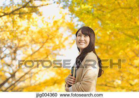 Young Japanese woman with book in a city park View Large Photo Image Stock Image - Young Japanese woman with book in a city park. Fotosearch