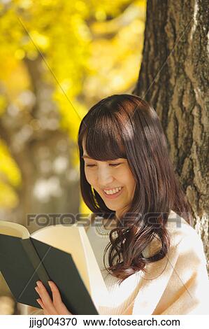 Young Japanese woman with book in a city park View Large Photo Image Stock Image - Young Japanese woman with book in a city park. Fotosearch