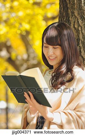 Young Japanese woman with book in a city park View Large Photo Image Stock Image - Young Japanese woman with book in a city park. Fotosearch