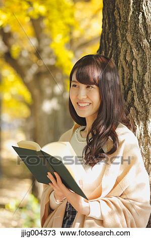 Young Japanese woman with book in a city park View Large Photo Image Stock Image - Young Japanese woman with book in a city park. Fotosearch