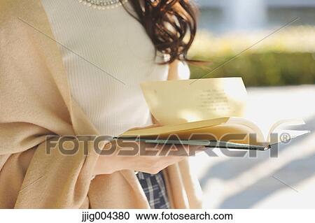 Young Japanese woman with book in a city park View Large Photo Image Stock Image - Young Japanese woman with book in a city park. Fotosearch