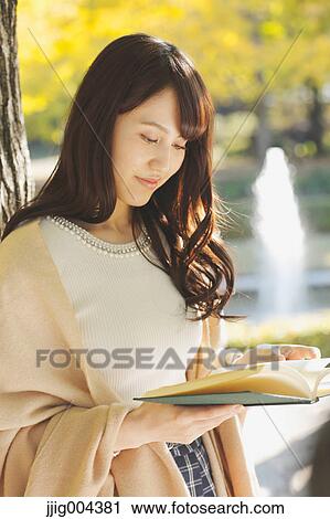 Young Japanese woman with book in a city park View Large Photo Image Stock Image - Young Japanese woman with book in a city park. Fotosearch