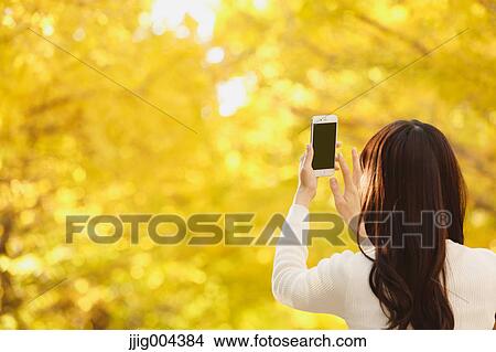 Young Japanese woman with smartphone in a city park View Large Photo Image Picture - Young Japanese woman with smartphone in a city park. Fotosearch