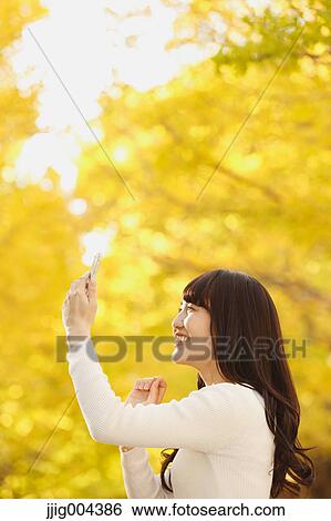 Young Japanese woman with smartphone in a city park View Large Photo Image Stock Photograph - Young Japanese woman with smartphone in a city park. Fotosearch
