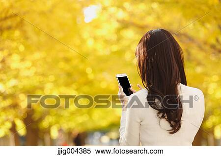 Young Japanese woman with smartphone in a city park View Large Photo Image Stock Photography - Young Japanese woman with smartphone in a city park. Fotosearch