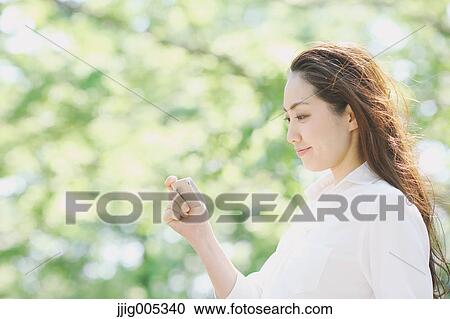 Young Japanese woman with smartphone surrounded by green in a city park View Large Photo Image Stock Image - Young Japanese woman with smartphone surrounded by green in a city park. Fotosearch