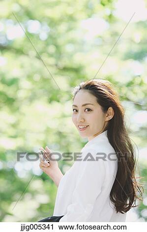 Young Japanese woman with smartphone surrounded by green in a city park View Large Photo Image Stock Image - Young Japanese woman with smartphone surrounded by green in a city park. Fotosearch