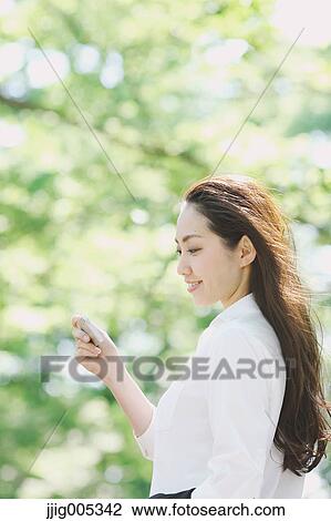 Young Japanese woman with smartphone surrounded by green in a city park View Large Photo Image Stock Image - Young Japanese woman with smartphone surrounded by green in a city park. Fotosearch