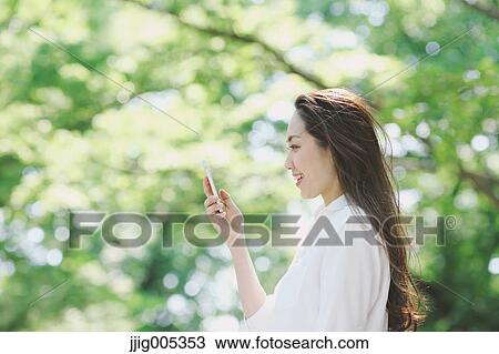 Young Japanese woman with smartphone surrounded by green in a city park View Large Photo Image Stock Image - Young Japanese woman with smartphone surrounded by green in a city park. Fotosearch