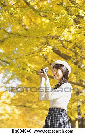 Stock Photograph - Young Japanese woman with vintage camera in a city park. Fotosearch