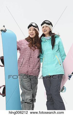 Stock Image - Young Japanese women wearing snowboard wear on white background. Fotosearch