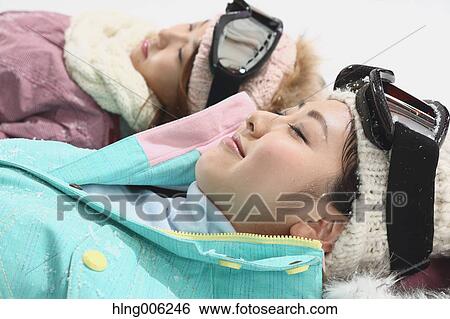 Stock Photograph - Young Japanese women wearing snowboard wear on white background. Fotosearch
