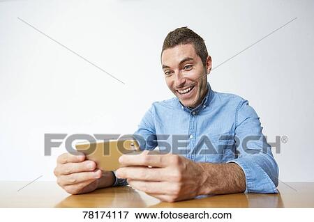 Caucasian man enjoying content on a smartphone View Large Photo Image Stock Photo - Caucasian man enjoying content on a smartphone. Fotosearch