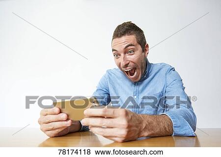 Caucasian man enjoying content on a smartphone View Large Photo Image Stock Photo - Caucasian man enjoying content on a smartphone. Fotosearch