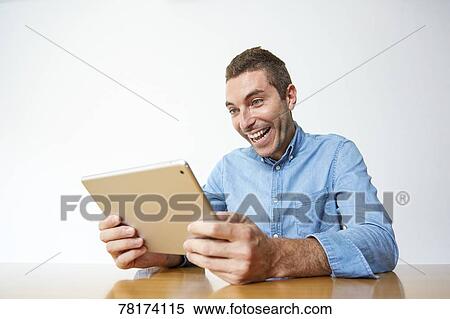 Stock Photography - Caucasian man enjoying content on a tablet. Fotosearch