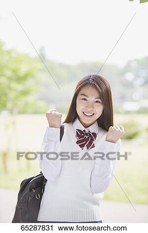 Stock Image - Cute Japanese high school student in a city park. Fotosearch