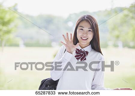 Stock Image - Cute Japanese high school student in a city park. Fotosearch