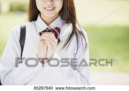 Stock Image - Cute Japanese high school student in a city park. Fotosearch