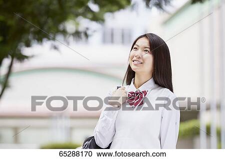 Stock Image - Cute Japanese high school student in a city park. Fotosearch
