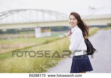 Stock Image - Cute Japanese high school student in a city park. Fotosearch