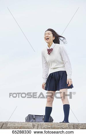 Stock Image - Cute Japanese high school student in a city park. Fotosearch