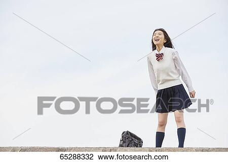 Stock Image - Cute Japanese high school student in a city park. Fotosearch