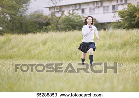 Stock Image - Cute Japanese high school student in a city park. Fotosearch