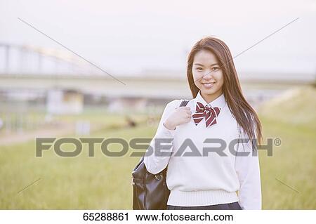 Stock Image - Cute Japanese high school student in a city park. Fotosearch