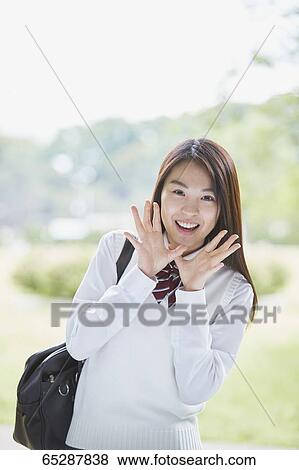 Stock Photo - Cute Japanese high school student in a city park. Fotosearch