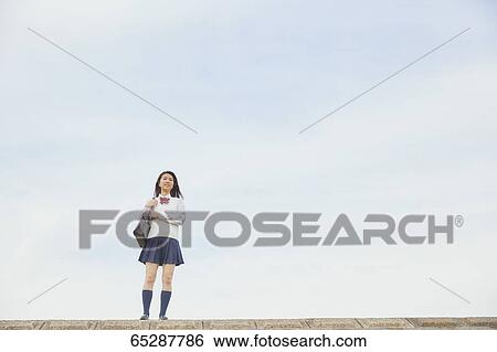 Stock Photograph - Cute Japanese high school student in a city park. Fotosearch
