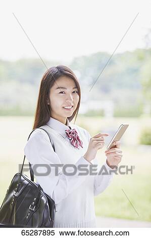 Stock Photography - Cute Japanese high school student in a city park. Fotosearch