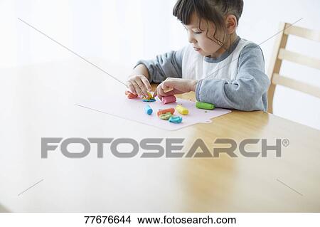 Picture - Cute Japanese kid playing with clay. Fotosearch