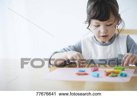 Stock Image - Cute Japanese kid playing with clay. Fotosearch