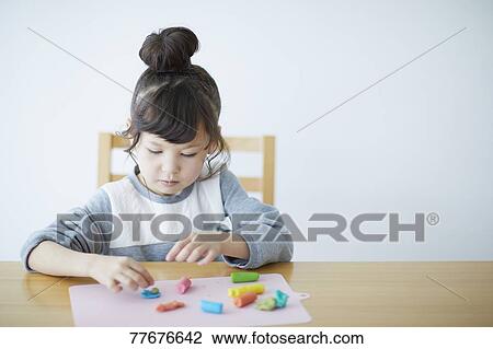 Stock Image - Cute Japanese kid playing with clay. Fotosearch